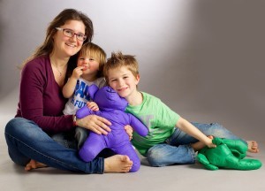 A candid studio portrait of a family with father and mother and two young kids wearing jeans and "save the future" T-shirts